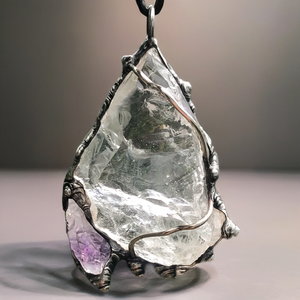Rough Clear Quartz pendant with rainbow adorned with small Amethyst point